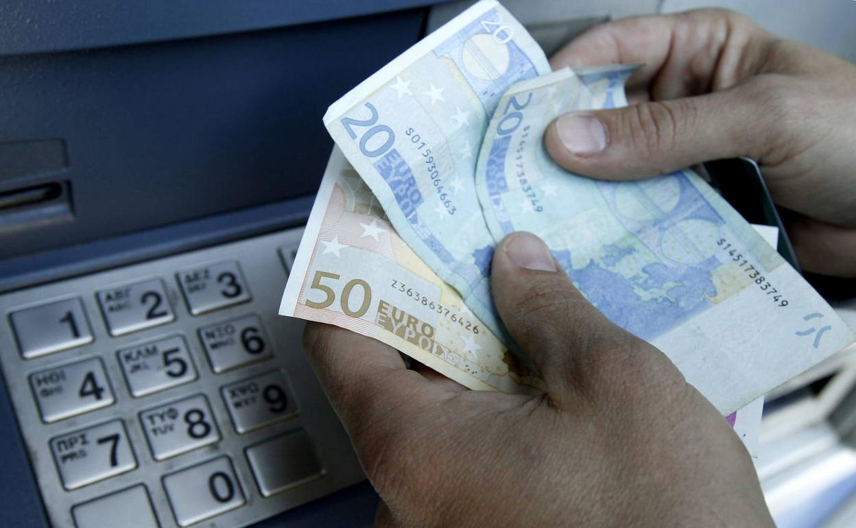 Una persona saca dinero de un cajero automático. 