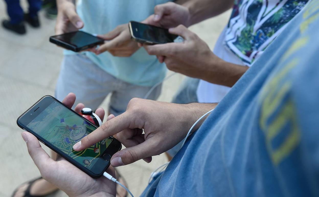 Varias personas juegan a Pokemon Go desde sus teléfonos móviles.