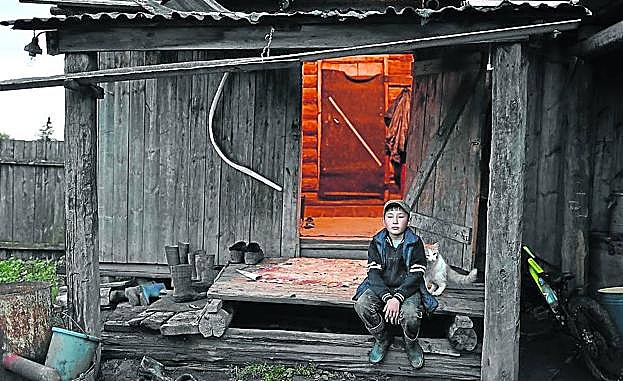 El niño, sentado a la puerta de su casa.