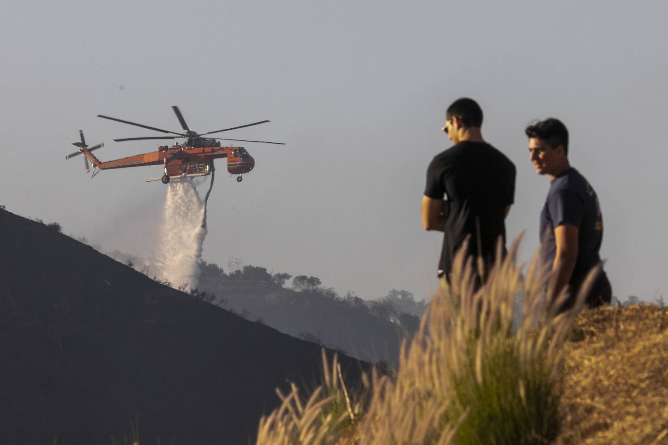 Varias personas observan helicópteros que arrojan agua sobre el llamado 'Getty Fire' cerca del famoso museo Getty Center en Los Ángeles