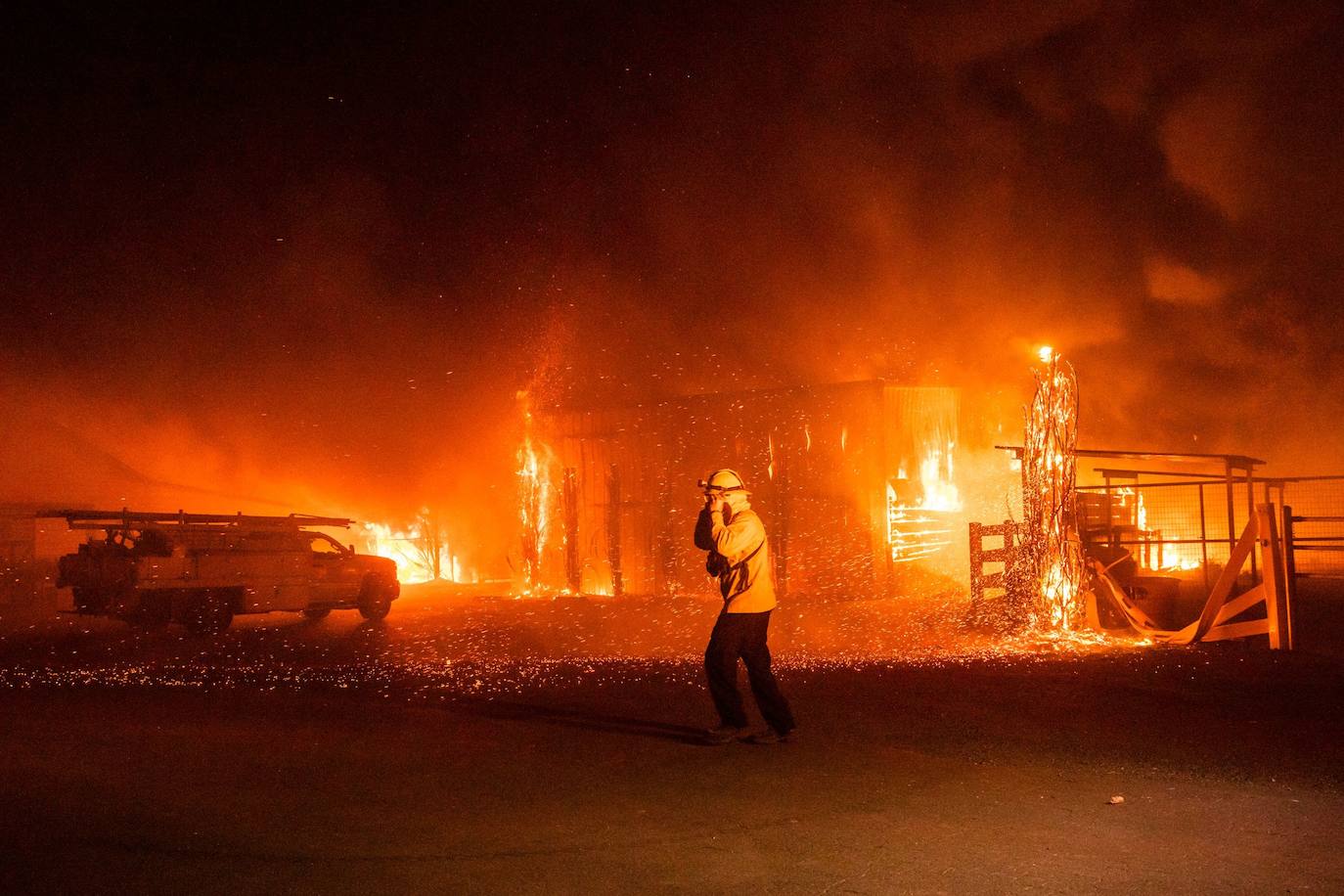 Bomberos frente a una granja en llamas durante el incendio Kincade