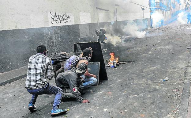 Ecuatorianos que protestan por la supresión de los subsidios a los combustibles se protegen en Quito de los gases lacrimógenos.