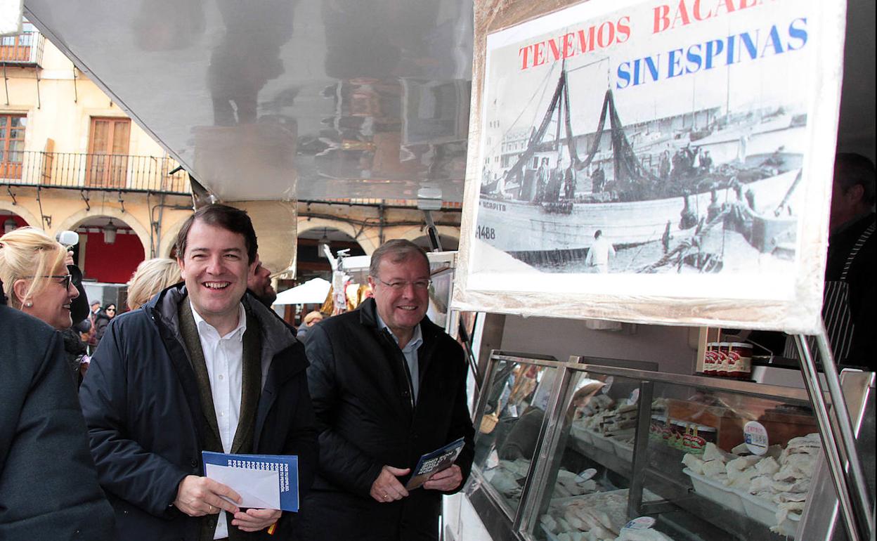 El presidente del PP de Castilla y León, Alfonso Fernández Mañueco (izquierda), junto a Antonio Silván (derecha), en el mercado de la Plaza Mayor de León. 