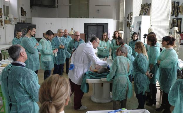 Los participantes en el taller práctico atienden las explicaciones del doctor Curiel durante la autopsia médico legal. 