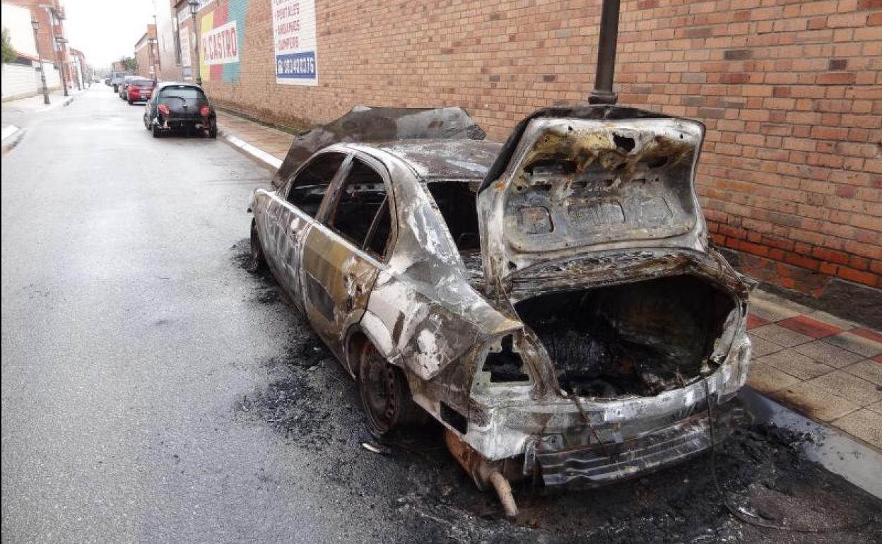 El coche carbonizado y el turismo (unos metros por delante) que resultó dañado por las llamas en Santovenia.