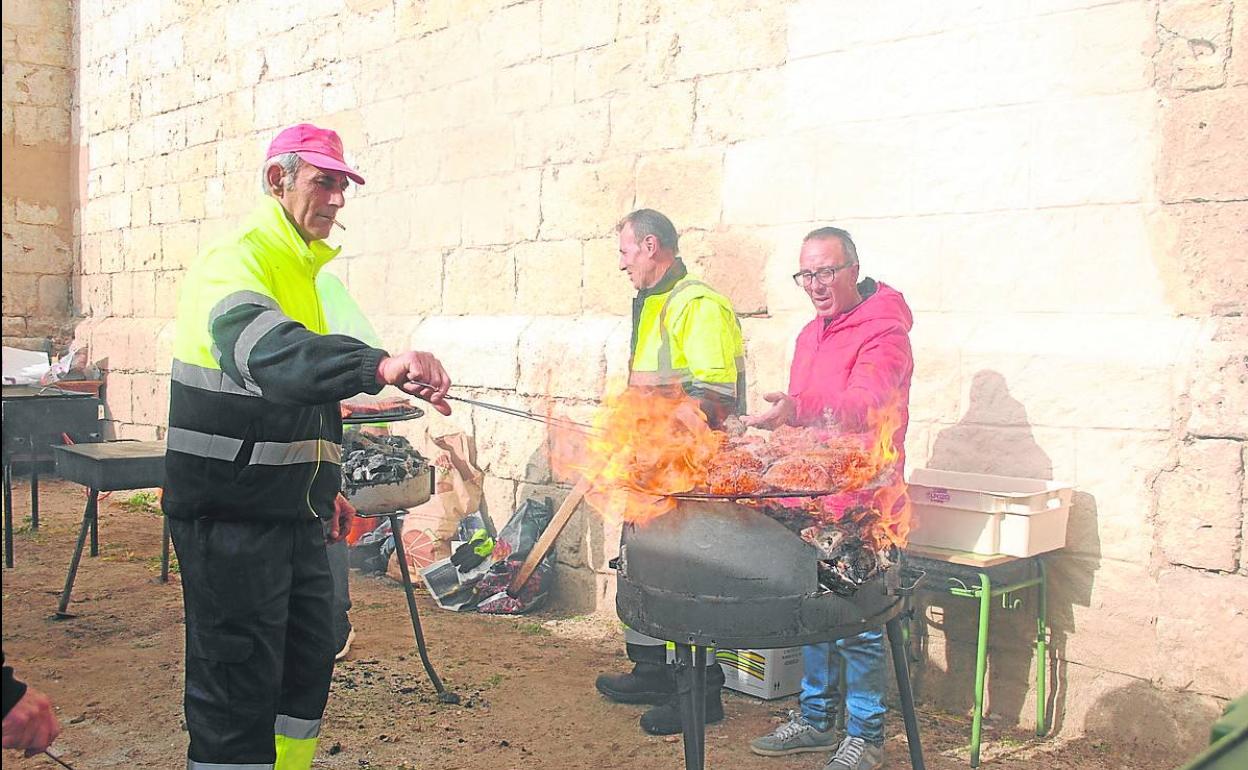 Los vecinos preparan chorizo al fuego. 
