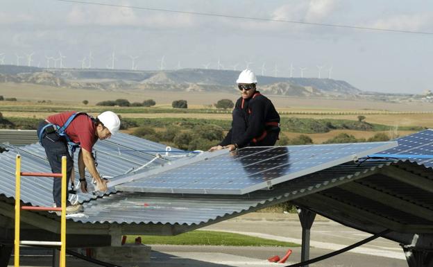 Obreros colocan unos paneles solares en el techo de una vivienda de Huesca. 