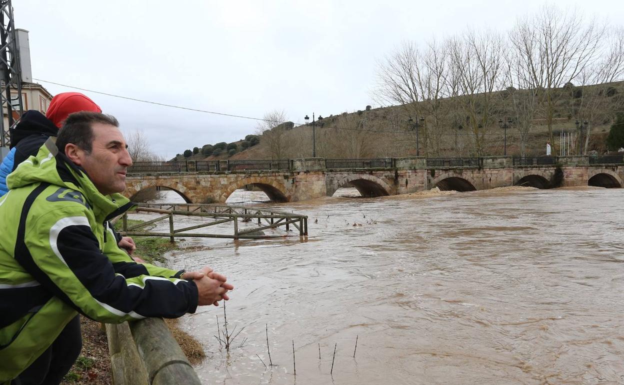 Dos vecinos observan la crecida del río Pisuerga a su paso por Alar del Rey. 