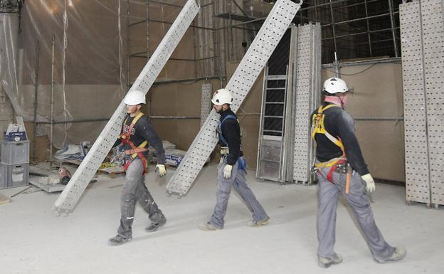 Tres operarios retiran los andamios del interior de la seo. 