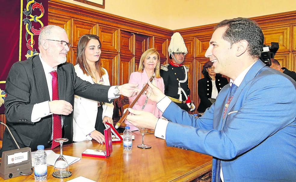 El concejal de mayor edad, Jesús Merino, del PSOE, entrega el bastón de mando al nuevo alcalde, Mario Simón.