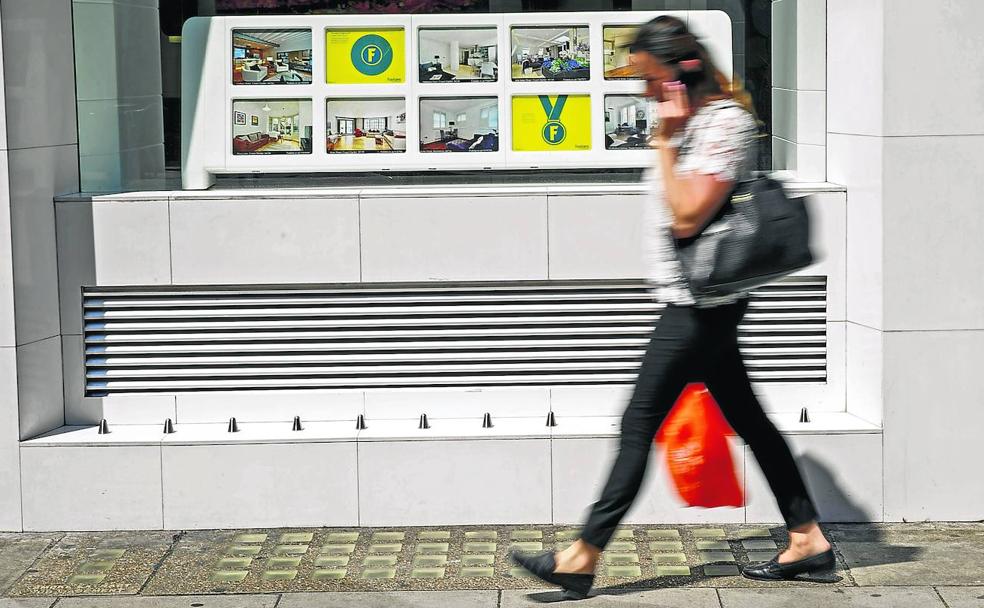 Una mujer camina junto a una agencia inmobiliaria del centro de Londres que incorporó elementos metálicos punzantes en su exterior. La medida provocó una protesta inmediata. 