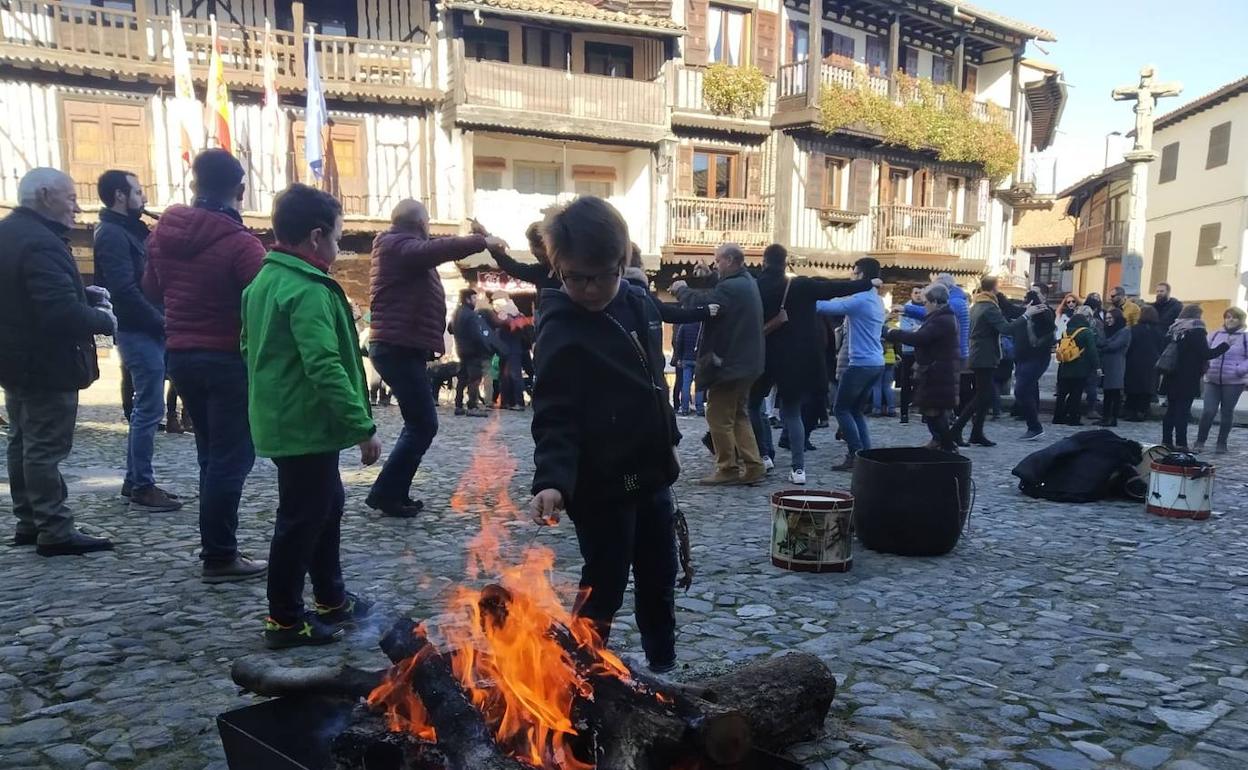 De fondo, los asistentes bailando mientras un niños es atraído por la lumbre.