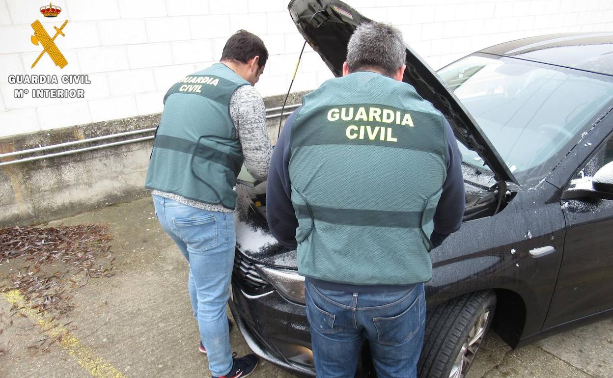 Dos guardias civiles supervisan el motor del turismo. 