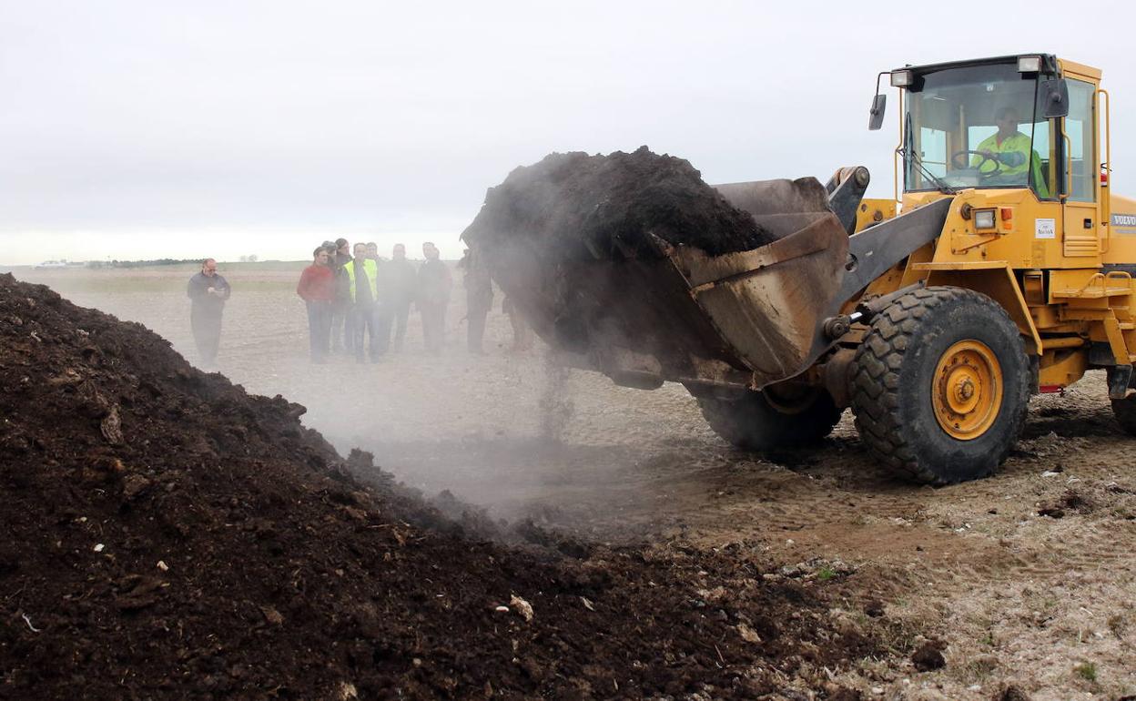 Una grúa retira los residuos de la planta de compostaje de Fuentepelayo. 