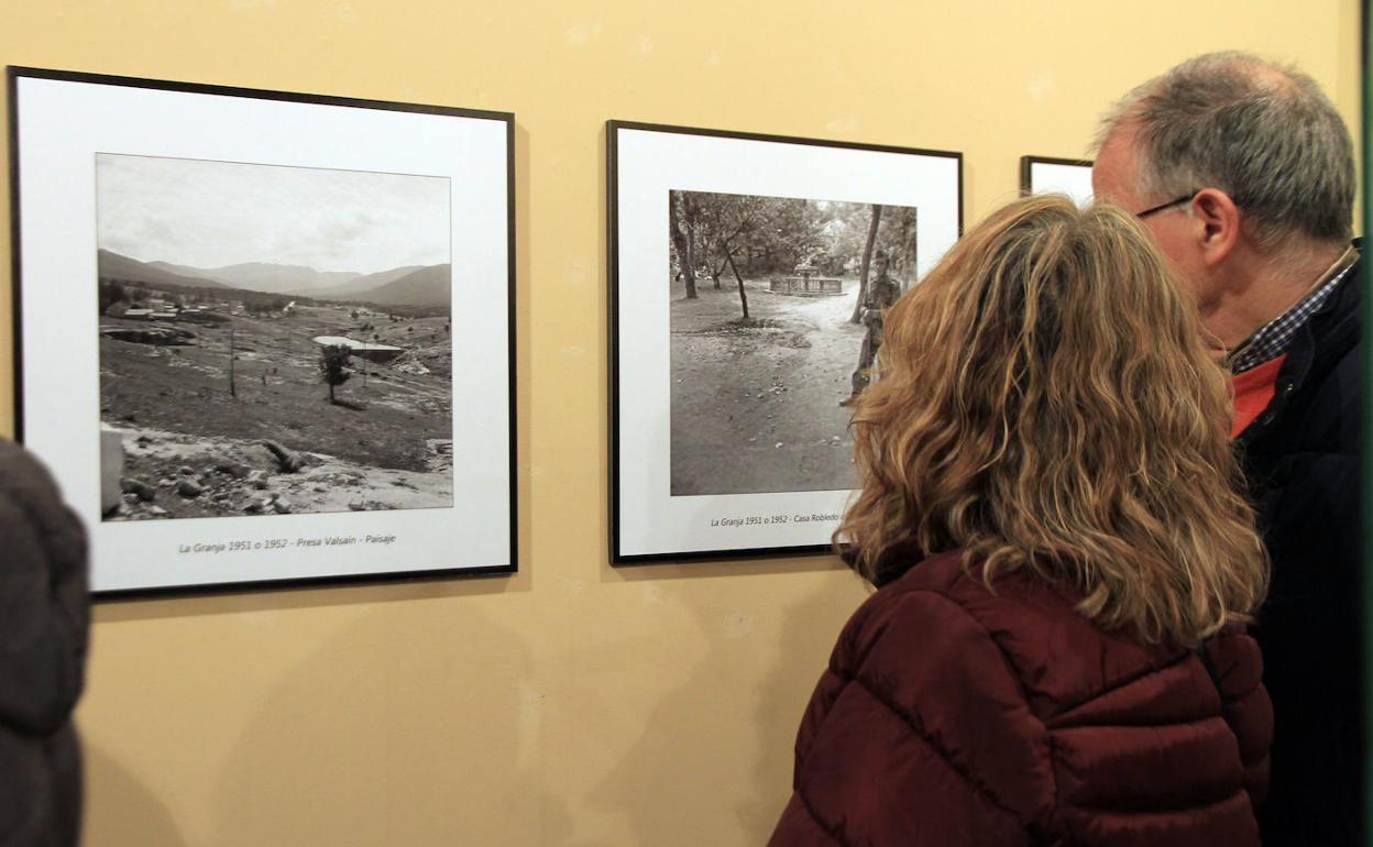 Varias personas contemplan algunas de las fotografías expuestas.