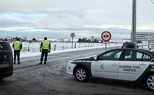 La Guardia Civil controla el tráfico complicado por el hielo y la nieve en las inmediaciones de Palazuelos y la Granja, este martes. 