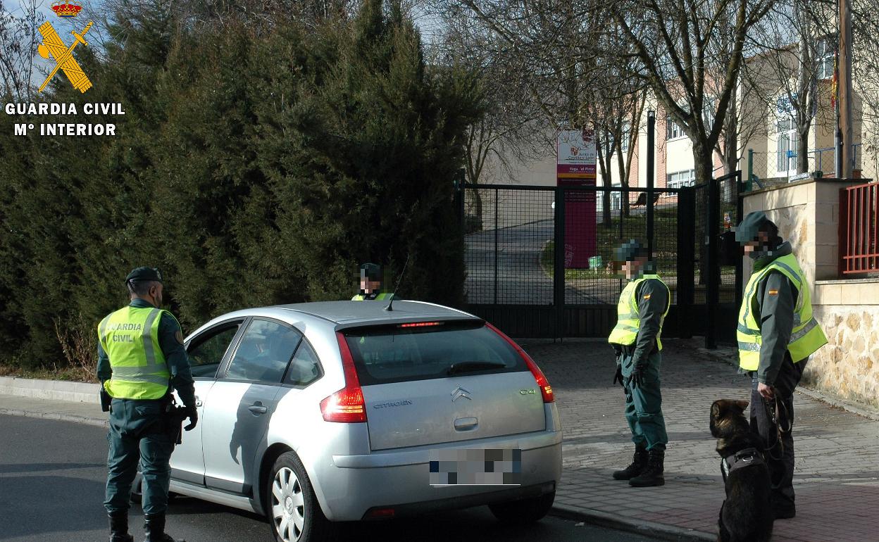 Agentes alrededor de un coche junto a un colegio. 