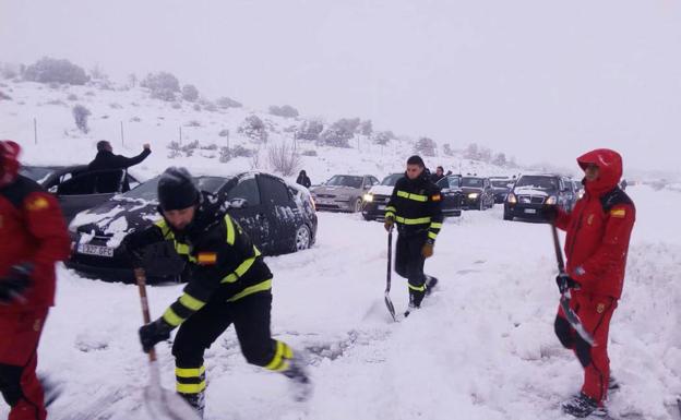 Agentes de la Guardia Civil y militares de la UME abren camino a coches atrapados en la AP-6 durante la nevada de la noche de Reyes de 2018. 