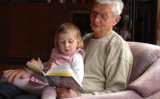 Un abuelo lee un cuento con su nieta.