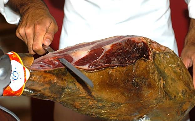 Un cortador de jamón lonchea una pieza.