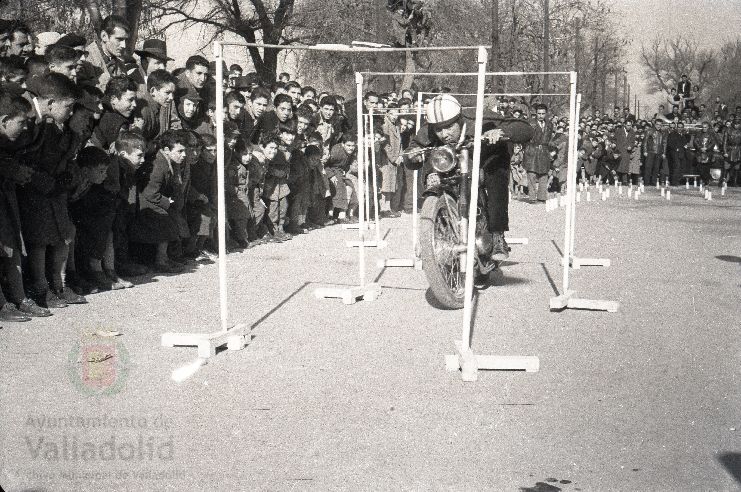 El domingo 19 de enero de 1958, veinte mil personas presenciaron la prueba que se celebró en el paseo alto de las Moreras | La prueba consistió en formar una barrera humana sobre una moto Vespa con diez y siete hombres abordo y así recorrer más de quinientos metros, batiendo el récord mundial que los ingleses habían establecido días antes | La 'Vespa' era conducida por Virgilio Collantes, el gran héroe del día