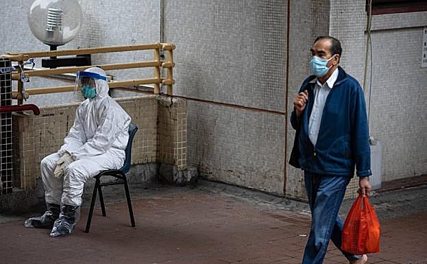 Dos hombres con mascarillas se protegen del virus en Hong Kong.
