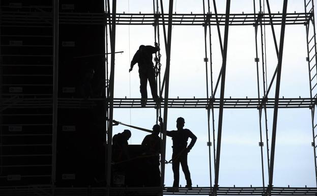 Trabajadores montan un andamio. 