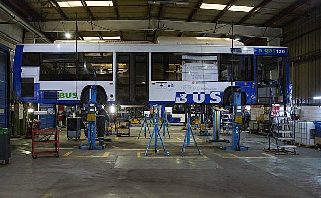 Un autobús elevado para su revisión en el interior de una de las naves de Auvasa en el polígono de Argales. 
