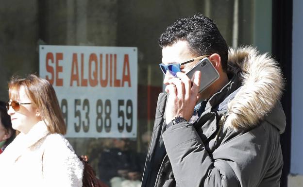 Un hombre habla a través del móvil por la Calle Mayor. 