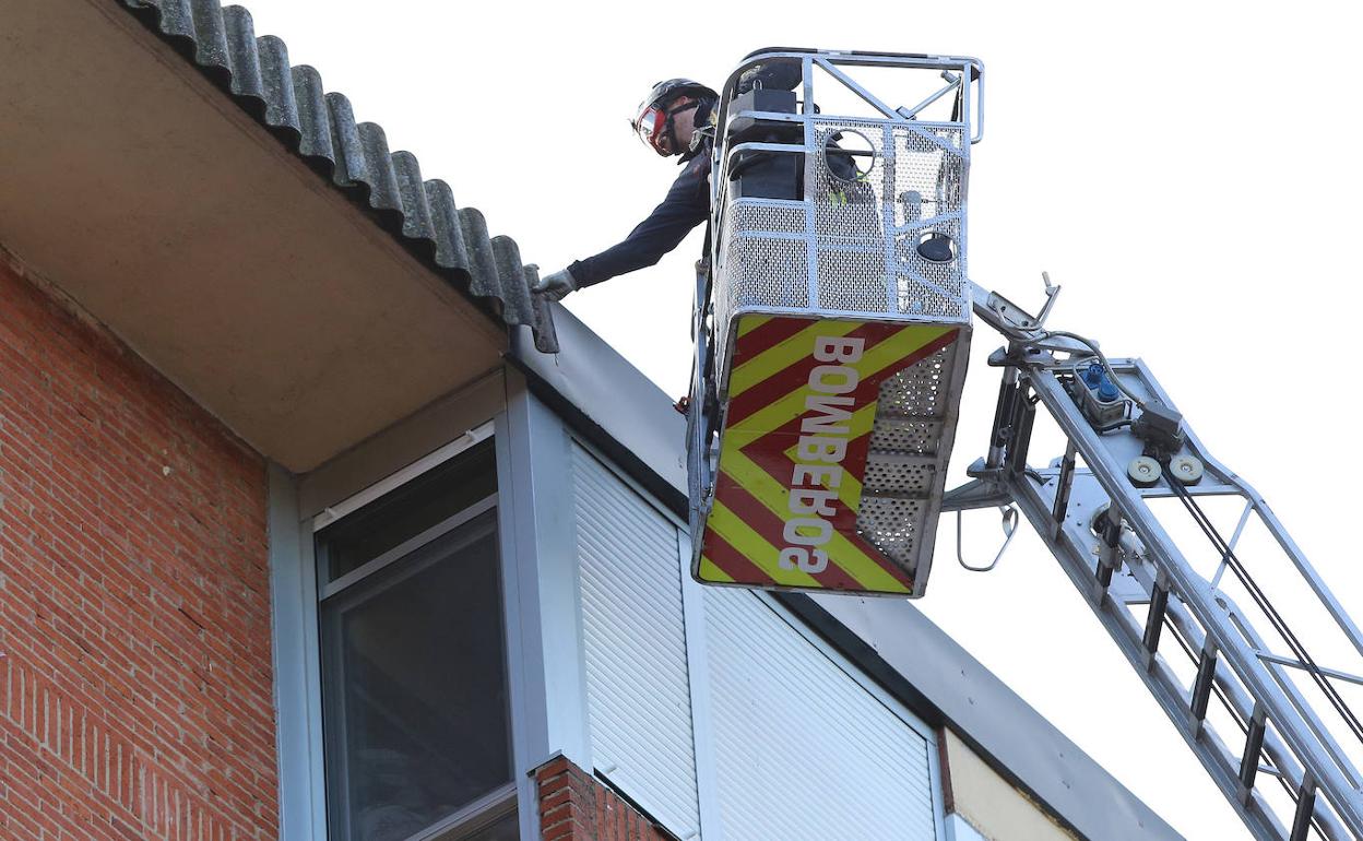 Un bombero de Palencia inspecciona el remate del tejado que ha causado daños en un vehículo que se encontraba aparcado en la calle Muñoz Bernal. 