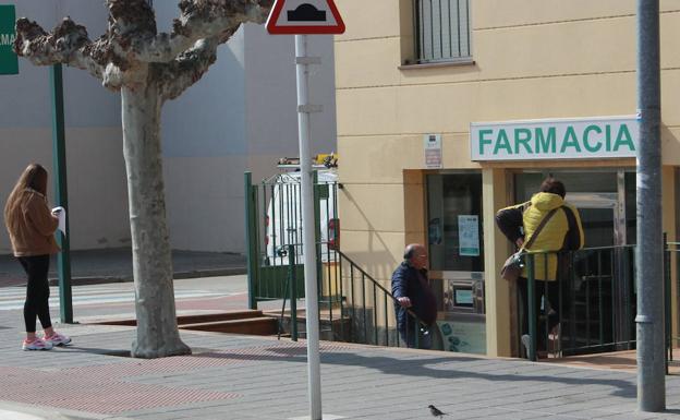 Varias personas esperan a la puerta de una farmacia para acceder, uno a uno, a comprar medicamentos. 