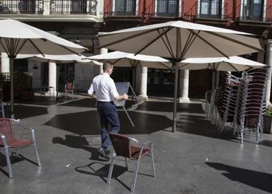 Imagen secundaria 1 - Los autobuses de Auvasa, parados en sus cocheras: un camarero recoge la terraza del Lion D'Or y un comercio cerrado en el centro.