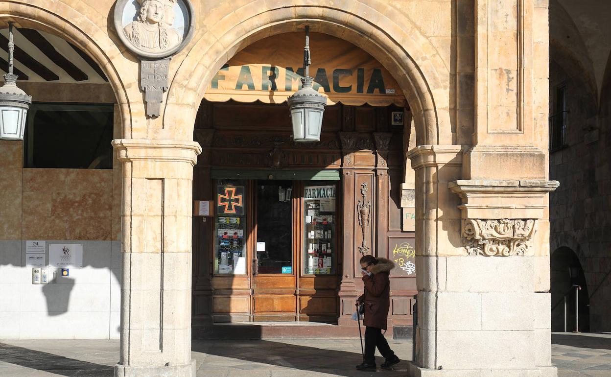 Una vecina de Salamanca camina ante una farmacia. 