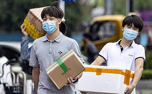 Dos jóvenes se protegen con mascarilla en Guangzhou, China.