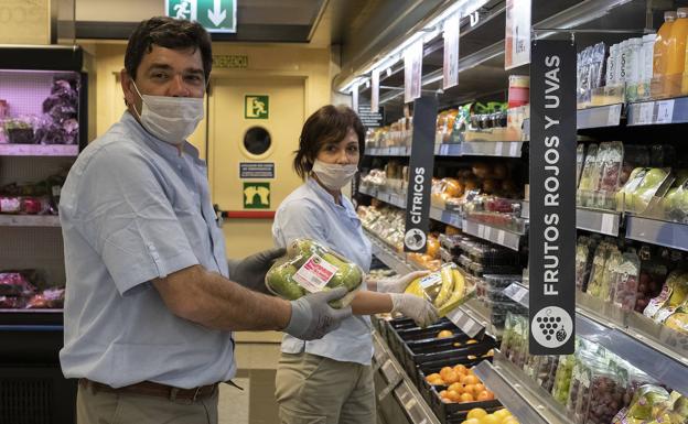 Javier Urizarna y Mayte Rodríguez reponen de productos la parte de frutería del supermercado.