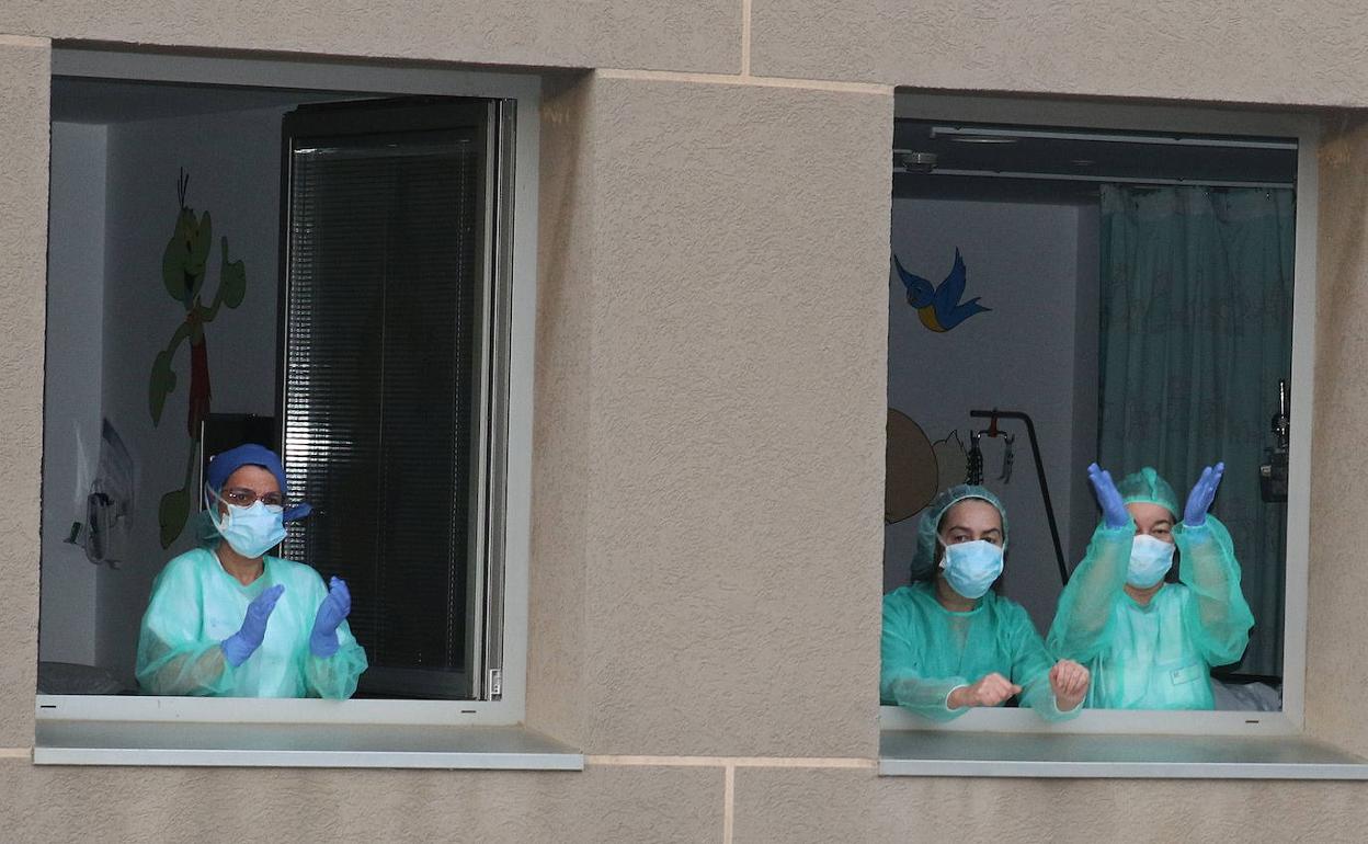 Enfermeras del Hospital General de Segova aplauden asomadas a unas ventanas. 
