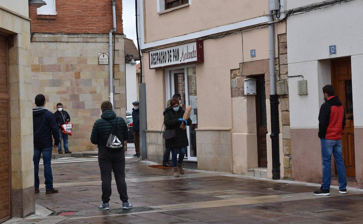 Varios aguilarenses esperan su turno en la calle para entrar en la panadería.