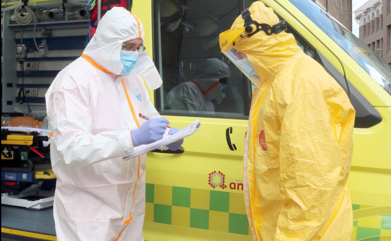 Un médico y un enfermero, a punto de subir a una ambulancia para tratar a un enfermo de coronavirus.