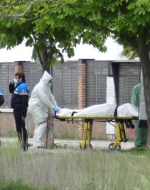 Imagen secundaria 2 - Arriba, Los efectivos de Criminalística examinan el cuerpo de la víctima en el parque junto al polideportivo; a la derecha, un guardia recoge una prenda hallada en el lago y a la izquierda, traslado del cuerpo al Instituto de Medicina Legal.