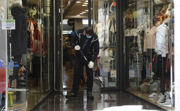 Un trabajador limpia el escaparate de una tienda de deportes. 
