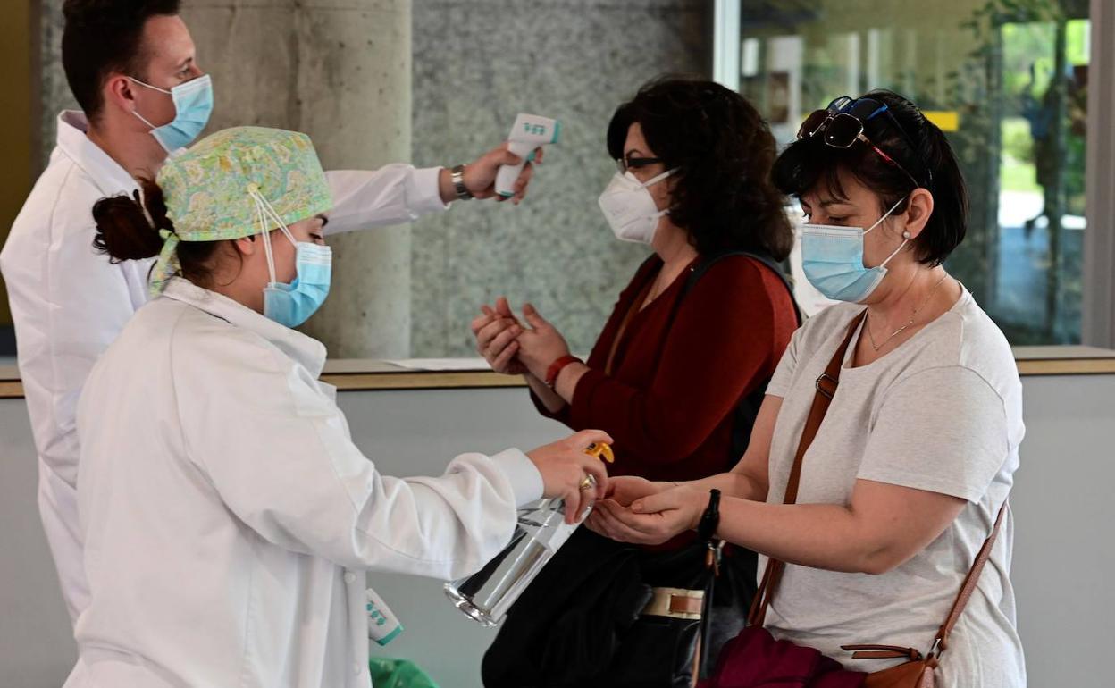 Enfermeros toman la temperatura a dos pacientes, en un hospital.