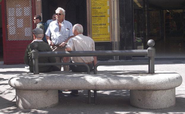 Unos pensionistas conversan en un banco.