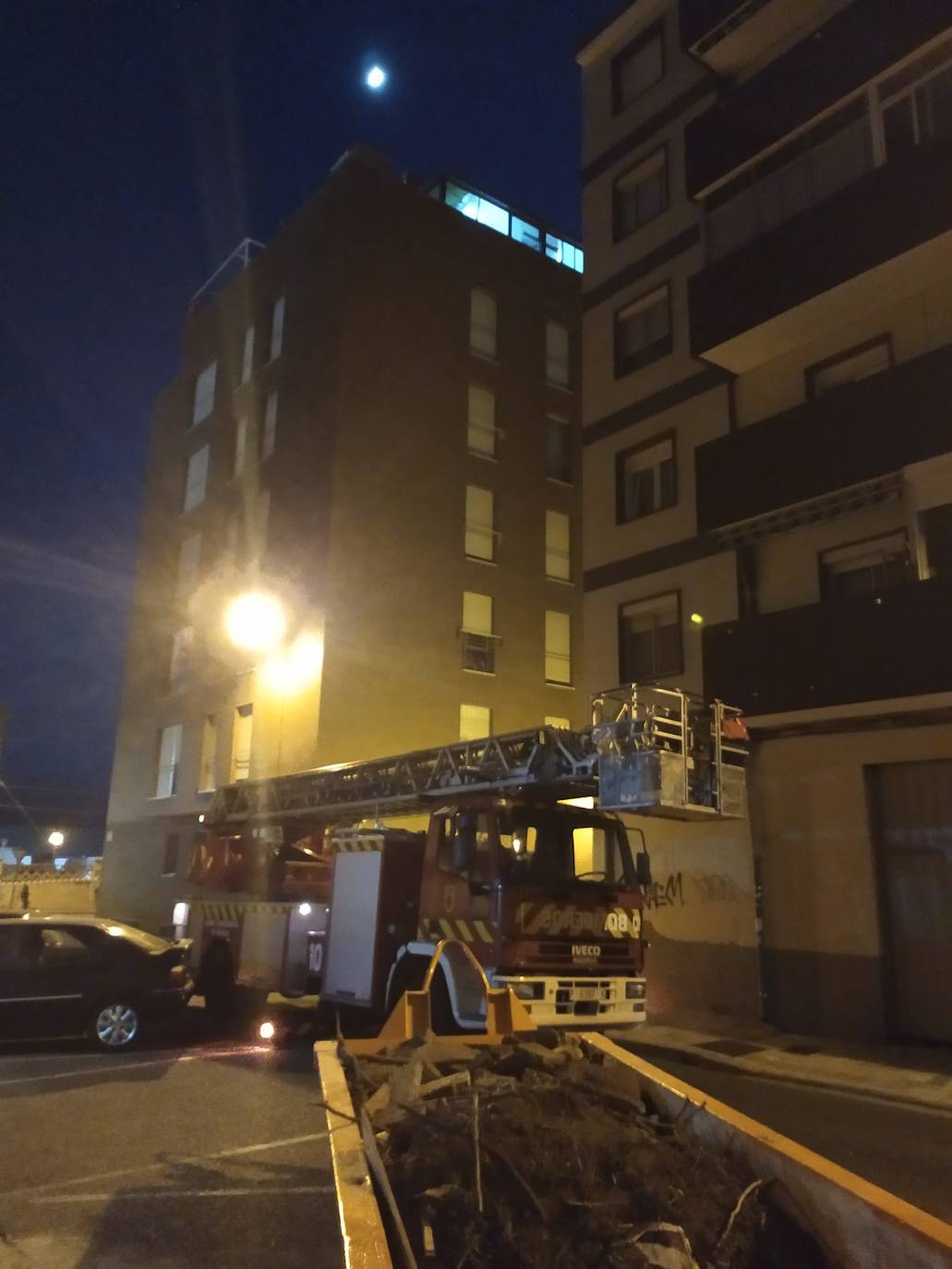 Los bomberos se retiran con la escala con la que accedieron a lo alto del edificio, anoche en la calle Anastasio Santamaría.