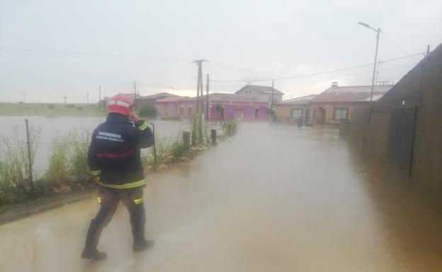 Un bombero se dirige a las viviendas próximas al regato. 