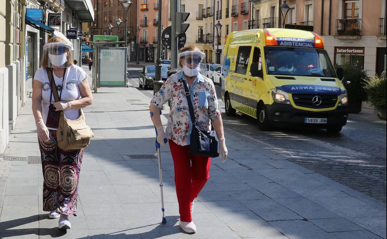 Dos mujeres caminan con pantallas protectoras por la calle. 