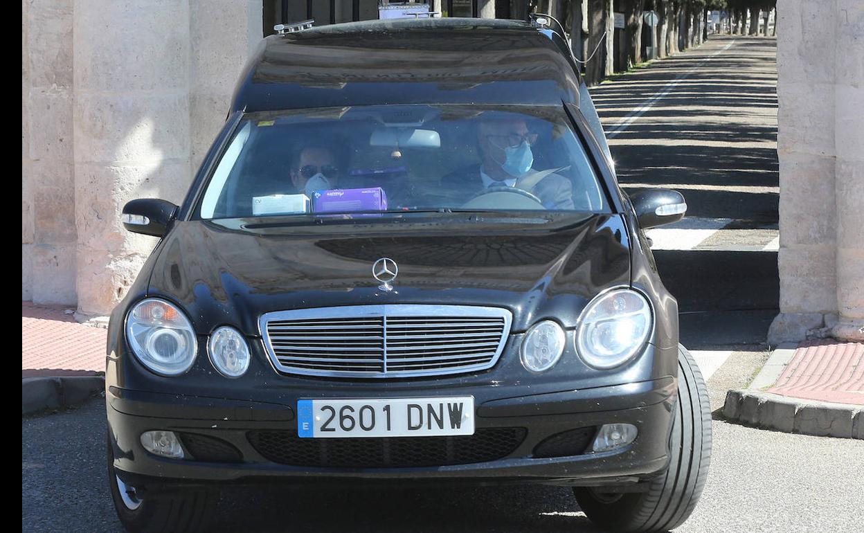 Un coche fúnebre, en el cementerio del Carmen de Valladolid, con los funerarios con mascarilla. 