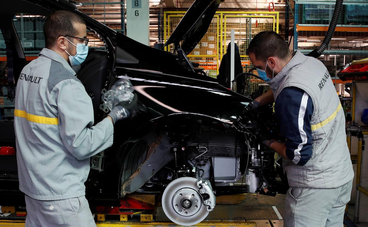 Dos operarios de Renault trabajan en una cadena de montaje en Francia.