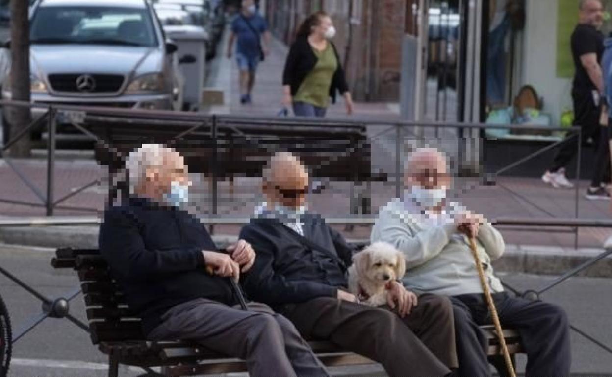 Tres conversan sentados en un banco de La Rondilla. 