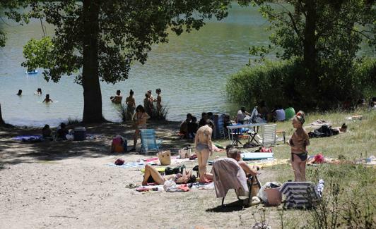 Varias familias en una playa fluvia del embalse de Encinas. 