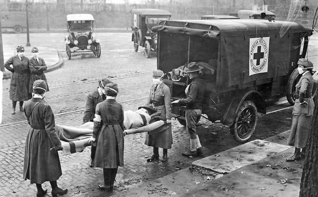 Voluntarios de Cruz Roja atienden a un enfermo por la gripe de 1918.